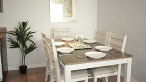 Een eettafel gedekt met borden, bestek en een bloevas.