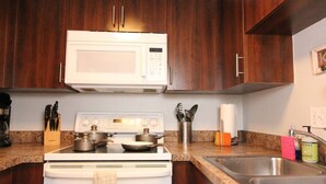 Een keuken met een witte magnetron, fornuis en een roestvrijstalen spoelbak.