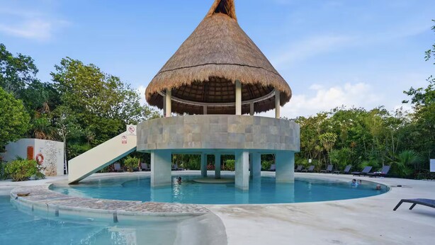 A pool with a thatched-roof structure, lounge chairs, and a no-smoking sign. - Casa Amaya - A comfortable place to enjoy the Riviera Maya with your family. (Puerto Morelos)