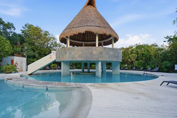 Ein Pool mit einer strohgedeckten Struktur, Liegestühlen und einem Rauchverbot-Schild.