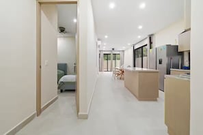 Eine moderne Küche mit Kochinsel, eine Essecke mit Stühlen und ein Schlafzimmer mit Bett und Vorhängen.
