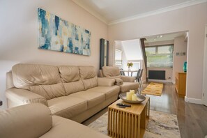 A living room with a beige sofa, a wooden coffee table, and a painting on the wall.