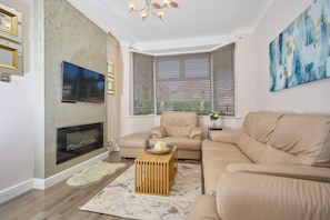 A living room with a fireplace, two sofas, a coffee table, and a painting on the wall.