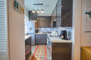 A modern kitchen with dark cabinets, a white countertop, and a coffee maker.