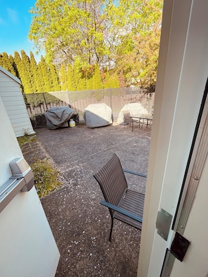 Ein Patio-Bereich mit überdachtem Tisch und Stühlen, einem überdachten Grill und einem Zaun.