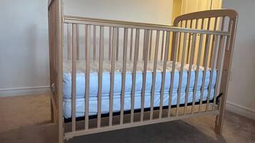 A crib with a mattress, a wooden headboard, and a metal rail.