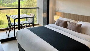 A modern bedroom with a large bed, a small table, and a chair. - Fully Equipped Suite Near JMC Airport (Rionegro)
