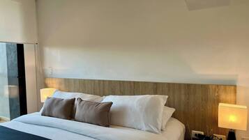A hotel room with a bed, bedside lamps, a telephone, and a wooden headboard.