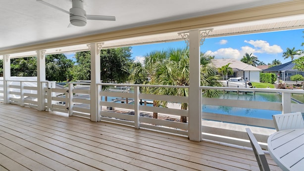 Un'area esterna coperta con piscina, ringhiere bianche e una ventola a soffitto.