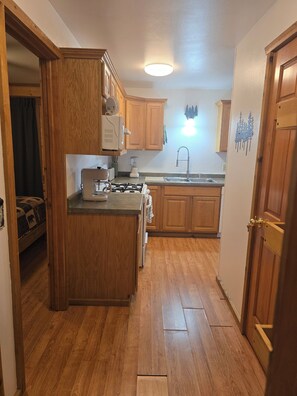 A kitchen with wooden cabinets, a stove, a sink, and a ceiling light.