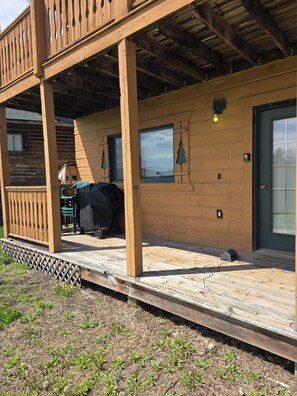 A wooden deck with a covered area, a door, and a window with a view.