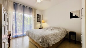 A bedroom with a bed, a ceiling fan, a window with curtains, a bedside table with a lamp, and a framed picture on the wall. - Caleta CostaBravaSi - Rest 650 m from the beach (Castell d'Aro)