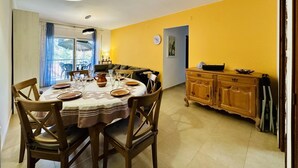 A dining area with a round table, chairs, a chandelier, a sofa, and a kitchen area with cabinets. - Caleta CostaBravaSi - Rest 650 m from the beach (Castell d'Aro)