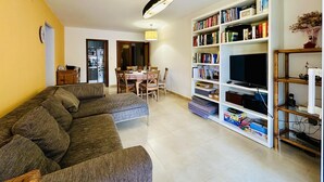 A living room with a sofa, dining table, chairs, a bookshelf, and a TV. - Caleta CostaBravaSi - Rest 650 m from the beach (Castell d'Aro)