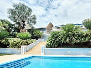 A swimming pool, stairs leading to a house, and tropical plants. - Luxurious and spacious Caribbean Villa with large private pool (Gros Islet)