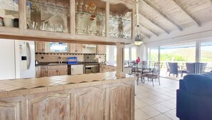 Una cocina amplia con una isla grande, un comedor con asientos exteriores y vistas al exterior.