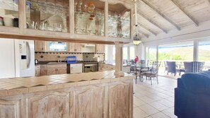 A spacious kitchen with a large island, a dining area with outdoor seating, and a view of the outdoors. - Luxurious and spacious Caribbean Villa with large private pool (Gros Islet)