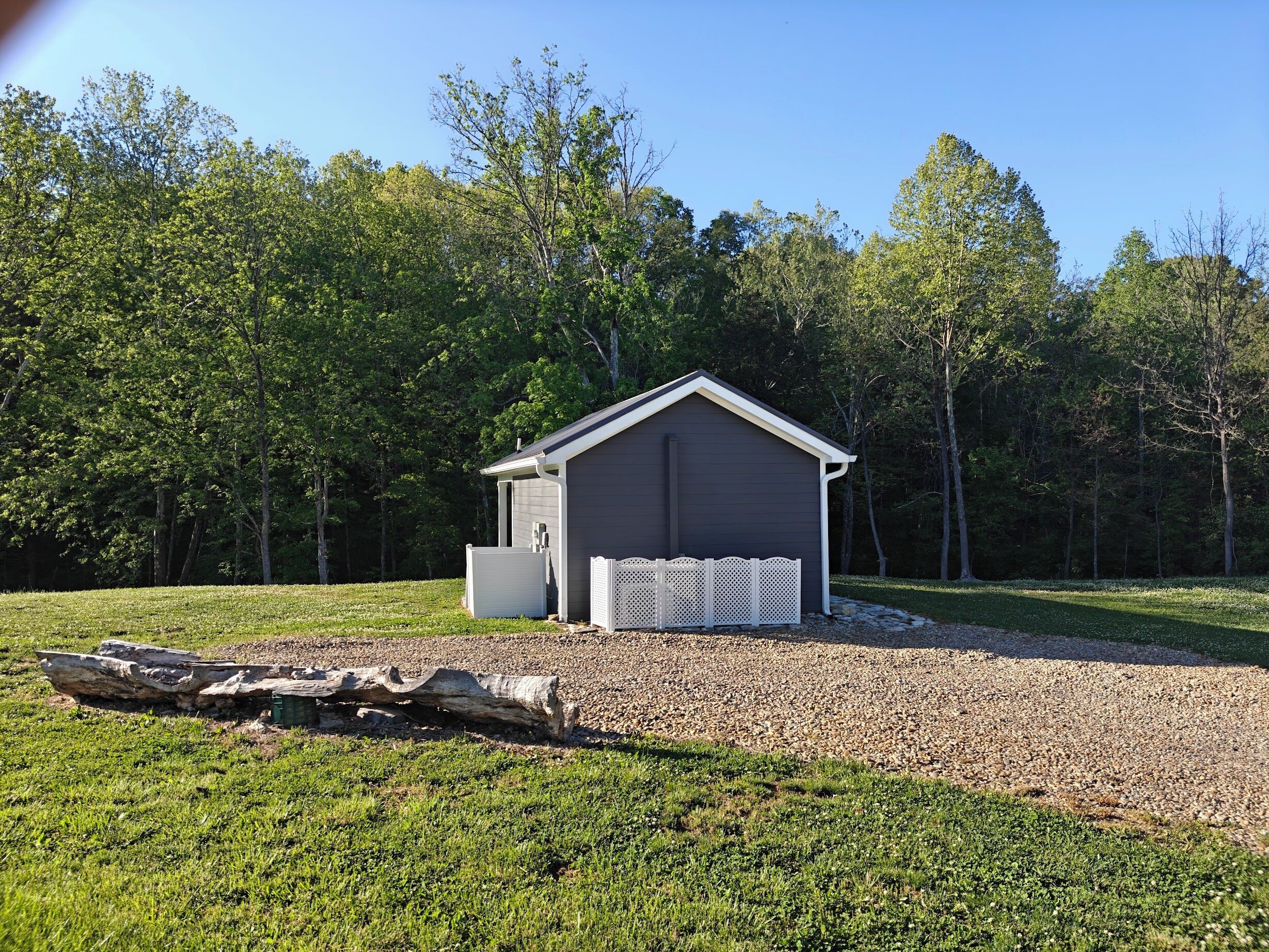 A small, single-story shed with a sloped roof, a front door, and a small porch area.