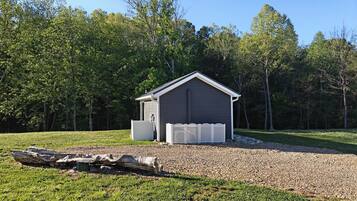 A small, single-story shed with a sloped roof, a front door, and a small porch area.