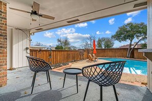 Estar coberto com piscina, duas cadeiras, uma mesa e um ventilador de teto.