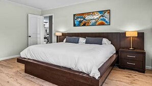 Ein Schlafzimmer mit einem Bett, Nachttischen, einem Deckenventilator und einem Bild an der Wand.