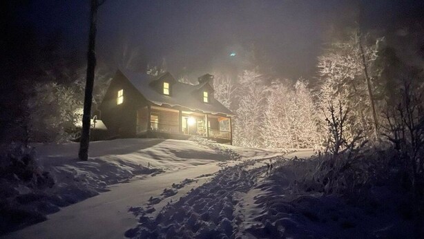 A snow-covered landscape with a wooden cabin illuminated by lights. - Mountain View Retreat (Ludlow)