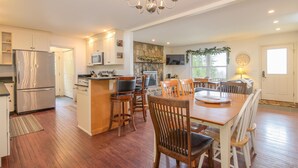 A spacious kitchen with a central island, wooden chairs, and a chandelier. - Mountain View Retreat (Ludlow)