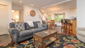 A living room with a sofa, coffee table, and a dining area with chairs and a table. - Mountain View Retreat (Ludlow)