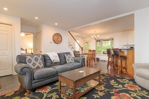Ein Wohnzimmer mit einer Couch, einem Couchtisch und einem Essbereich mit Stühlen und einem Tisch.