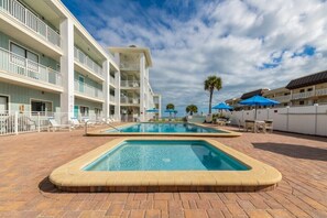 A hotel with a swimming pool, multiple balconies, and outdoor seating areas. - Delightful, Cozy Modern Apartment By The Ocean @Coastal Waters (New Smyrna Beach)