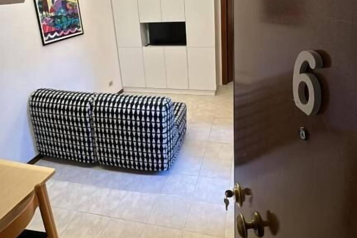 Un interno moderno con una scala, un divano, una TV e una porta con il numero 6.