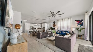 Uma sala de estar moderna com um sofá, mesa de centro e uma área de jantar ao fundo.