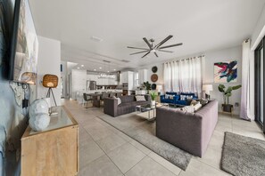 A modern living room with a sofa, coffee table, and a dining area in the background. - 6BR Stylish Reunion Villa • Pool • Near Disney (Reunion)