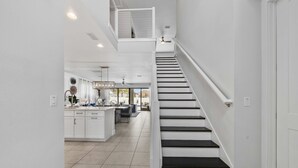 Uma cozinha moderna com armários brancos, uma ilha central e um espaço de refeições com mesa e cadeiras.