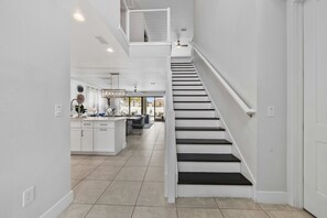 A modern kitchen with white cabinets, a central island, and a dining area with a table and chairs. - 6BR Stylish Reunion Villa • Pool • Near Disney (Reunion)