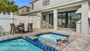 Uma área de piscina com hidromassagem, mobiliário externo e um terraço coberto.