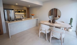 A modern kitchen with a central island, white dining table with chairs, and a round mirror on the wall. - Elegant, luminous and modern apartment in Zapopan (Zapopan)