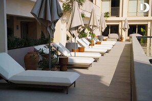 A poolside area with sun loungers, umbrellas, and potted plants. - Zapopan apartment with pool and gym (Zapopan)