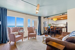 A living room with a sofa, armchair, and dining area with a view of the ocean. - Stunning Ocean Views, Pinnacle Port A-108 (Panama City Beach)