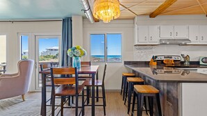 A modern kitchen with a central island, white cabinets, and a view of the ocean. - Ocean Views, Pinnacle Port A-108 (Panama City Beach)
