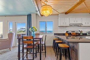 A modern kitchen with a central island, white cabinets, and a view of the ocean. - Stunning Ocean Views, Pinnacle Port A-108 (Panama City Beach)