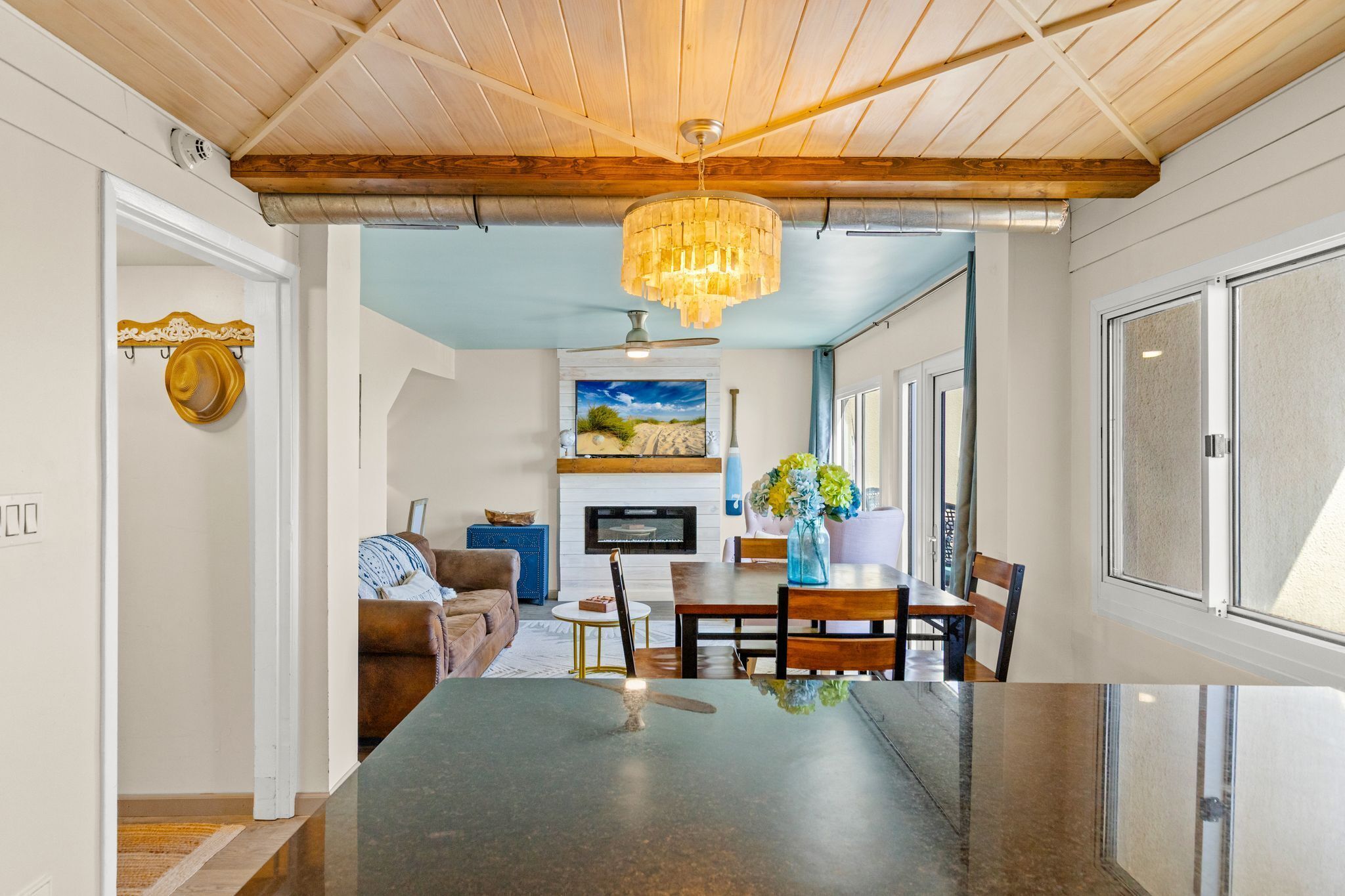 Una cocina moderna con una isla central, un comedor con mesa y sillas de madera, y una sala de estar con sofá y chimenea.