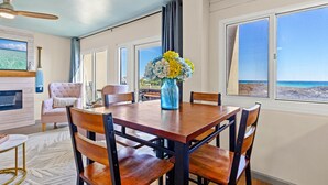 A spacious room with a large dining table, chairs, a fireplace, and a view of the beach. - Ocean Views, Pinnacle Port A-108 (Panama City Beach)