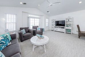 A spacious living room with a white round coffee table, grey sofas, a television, and a ceiling fan. - Beautiful 3 Bedroom Beach Condo Steps to Beach and Boardwalk Sleeps 8 (Wildwood)