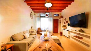 Ein Wohnzimmer mit Couch, Fernseher und einem Couchtisch aus Holz, sowie einer roten Decke.
