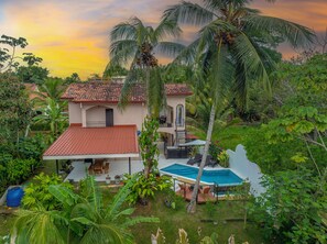 Ein Haus mit Ziegeldach, Pool und üppiger Bepflanzung.