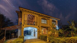 Uma casa de dois andares com varanda, alpendre coberto e fachada de pedra.