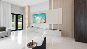 Una sala moderna con un televisor grande, un sofá, una mesa de centro y una zona de comedor.