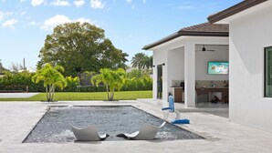 Una casa moderna con piscina, un patio cubierto y un televisor montado en la pared.