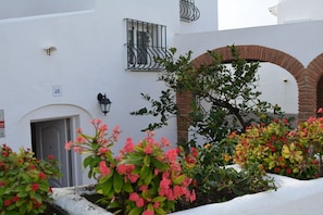A white building with a door, a window with black metal bars, and a brick archway. - Chalet by the Sea, with private parking, common swimming pools and tennis court (AN)